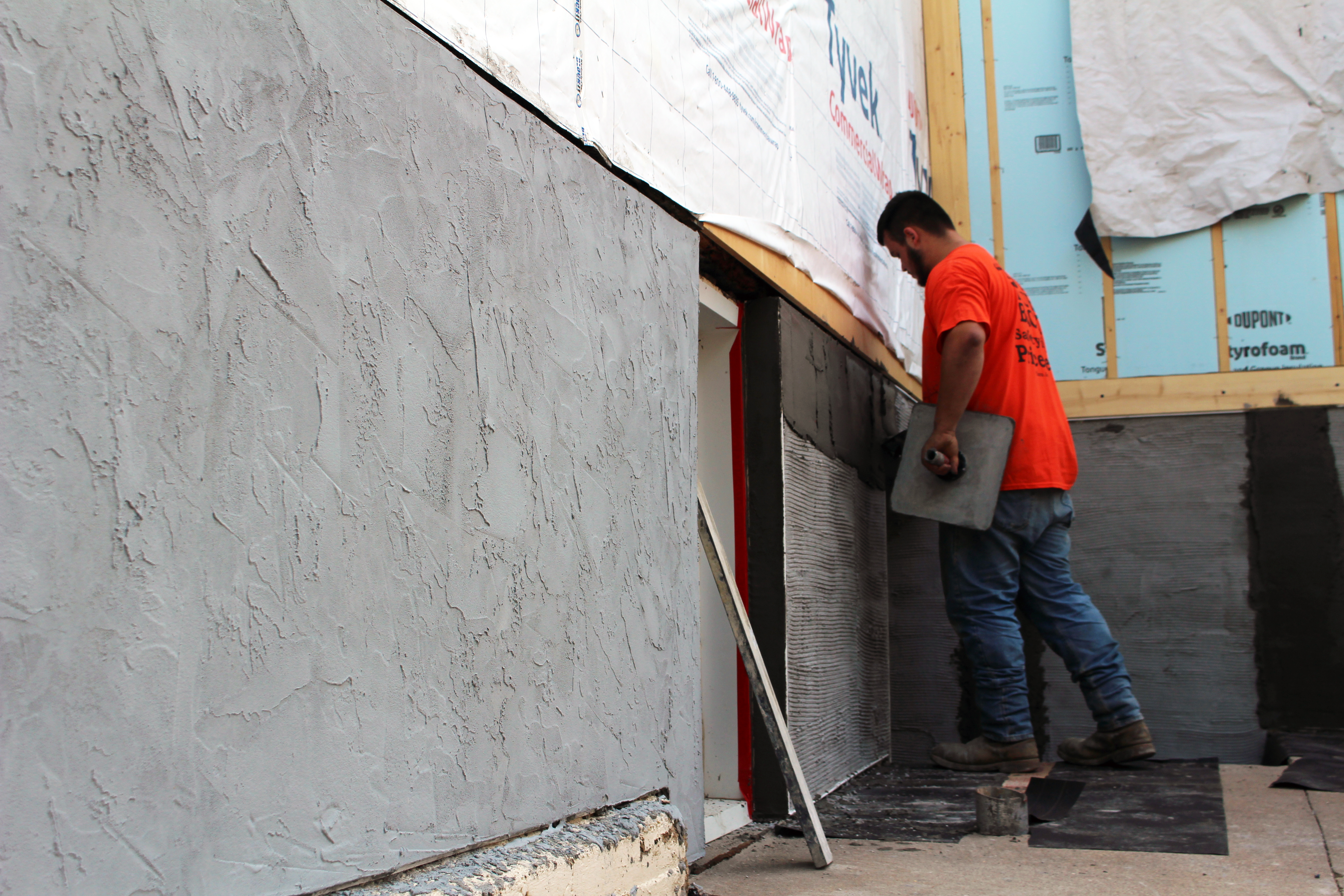 Man applying stucco to side of building